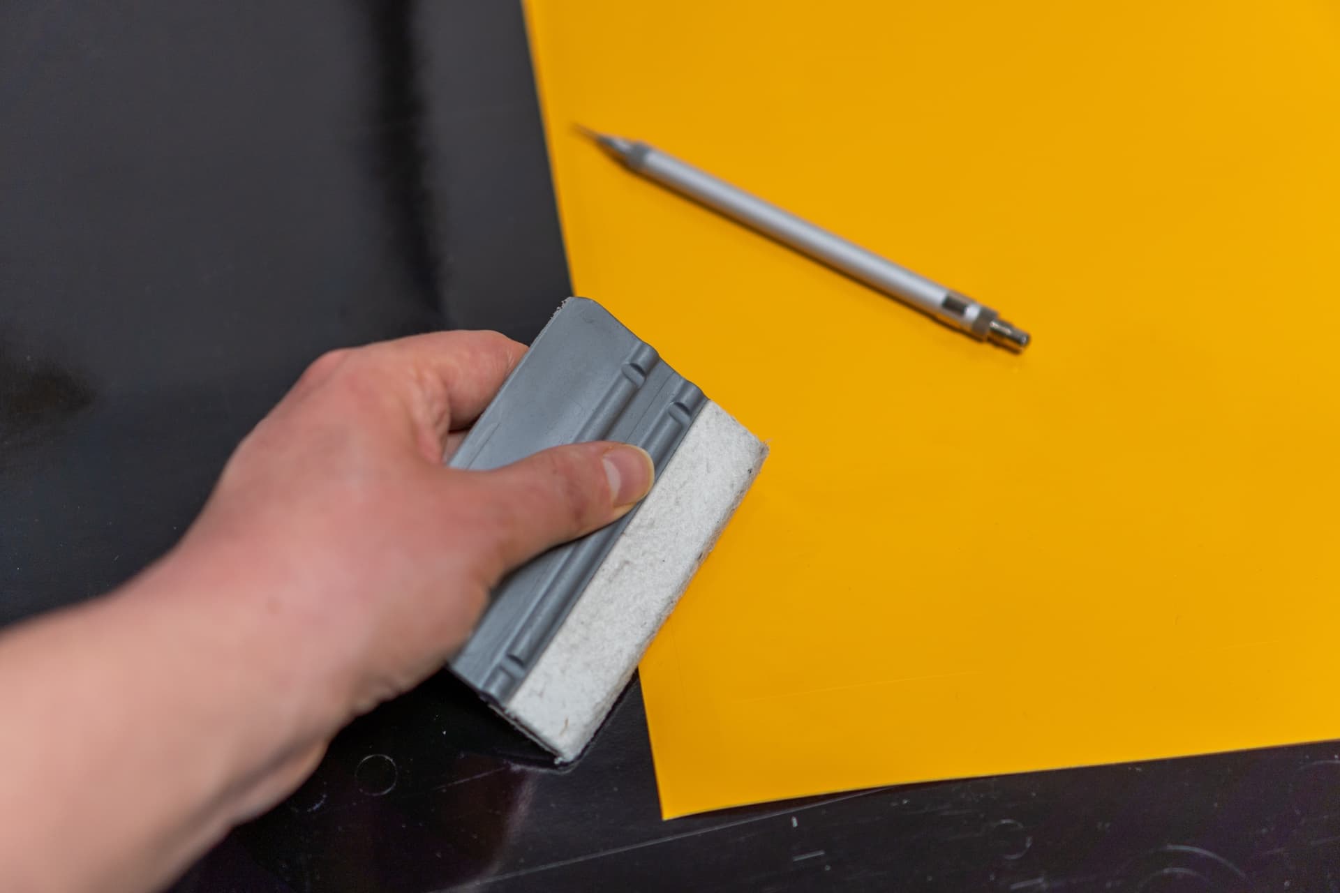 Representative close-up of a craftsperson applying vinyl with a squeegee